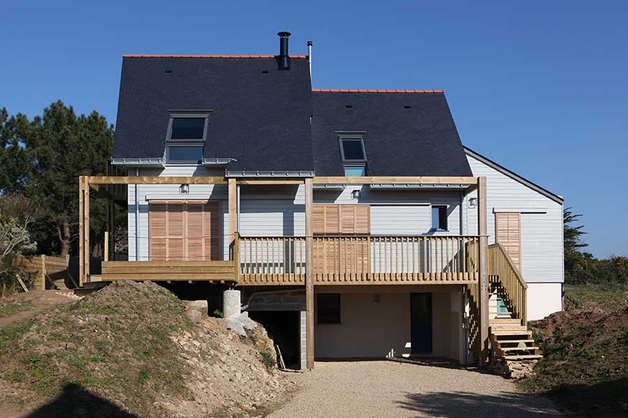 Construction d'une maison à ossature bois (bardage en bois peint) avec toitures en ardoise, dans le Morbihan